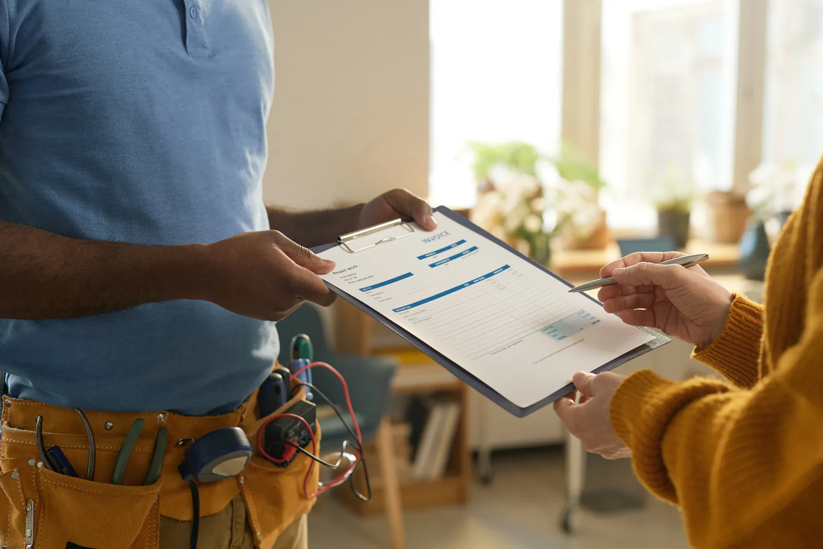 Plumber handing a homeowner a quote on a clipboard